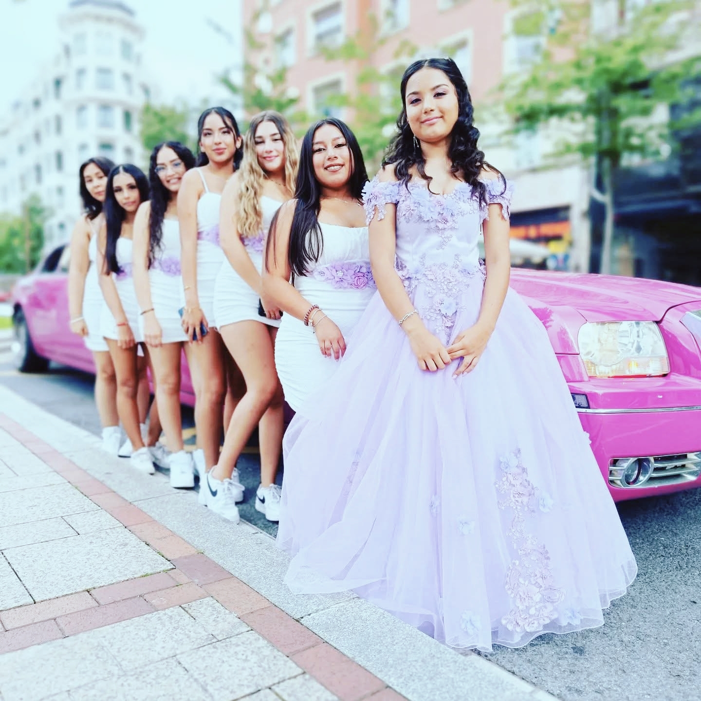 Limusina Fiesta 15 años en Barcelona Niña de 15 años sonriente frente a una limusina rosa, con cuatro damas de honor detrás, durante una fiesta de quince años
