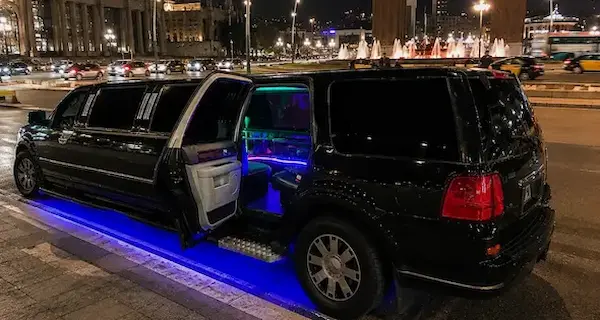 Limusina Lincoln Navigator negra vista de perfil, con luces LED iluminando la parte inferior del vehículo.