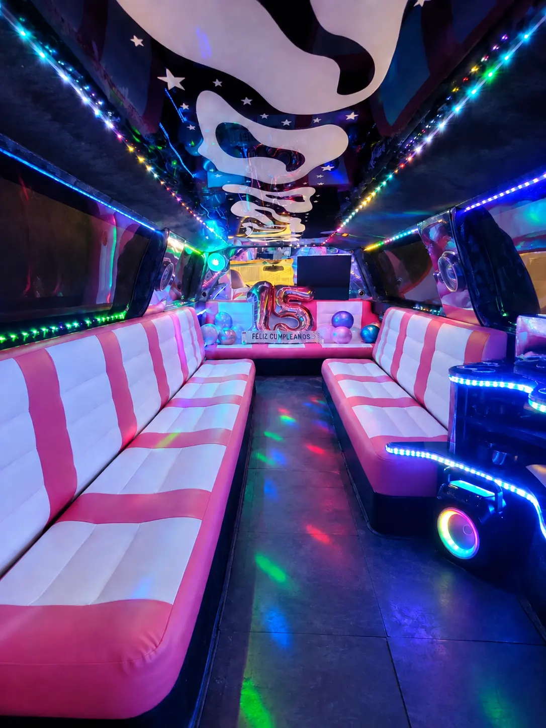 Interior de una limusina Lincoln Navigator rosa para fiesta 15 años equipada con iluminación LED, karaoke, barra y amplios asientos tipo sofá cama.